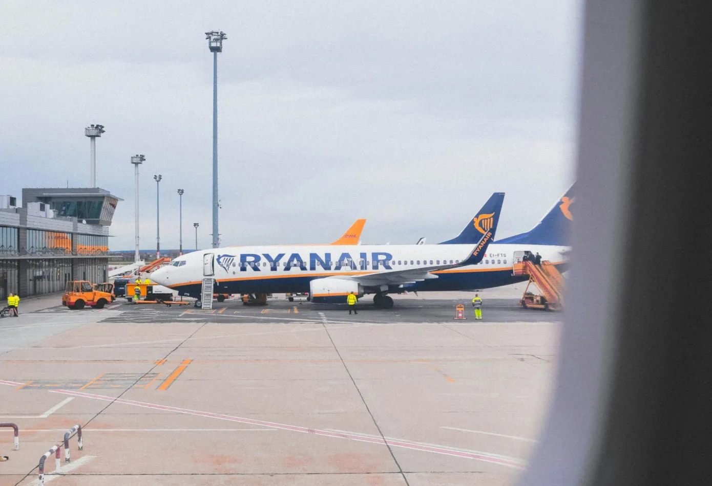 Passenger aircraft parked at an airport apron, seen through a terminal window