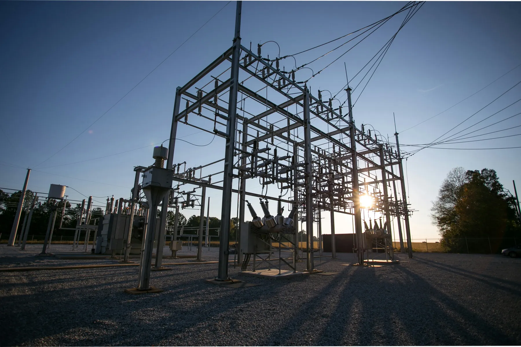 Electrical substation with switchgear and power lines at sunset