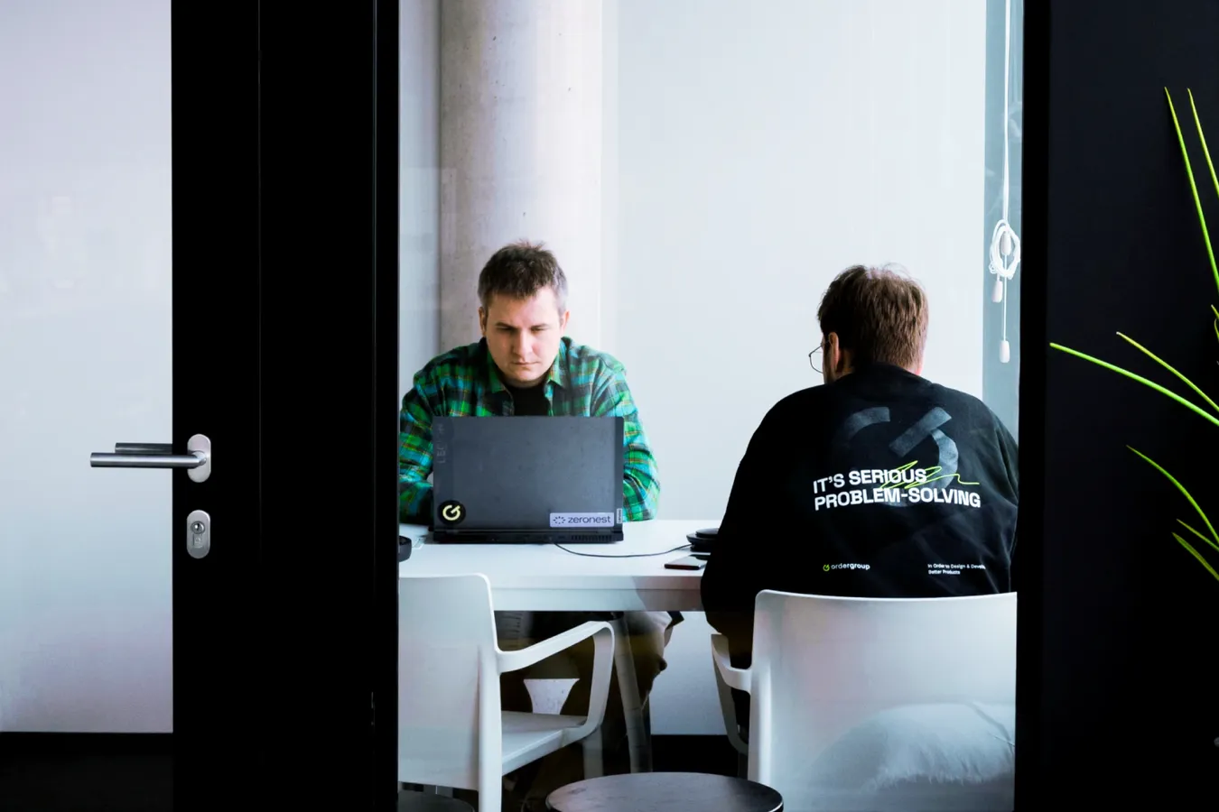 Two colleagues working together on a laptop in a bright office space