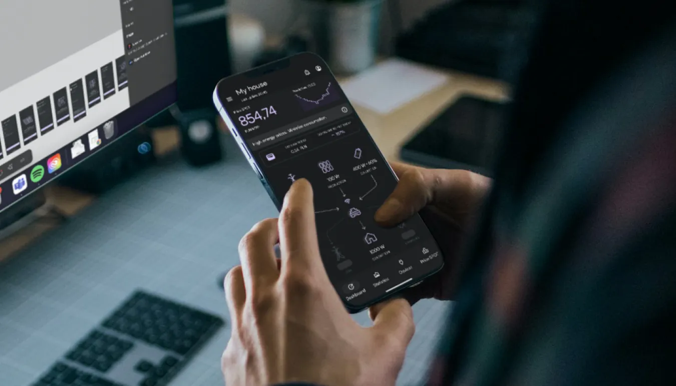Designer working on mobile app UI in Figma with energy management app on smartphone