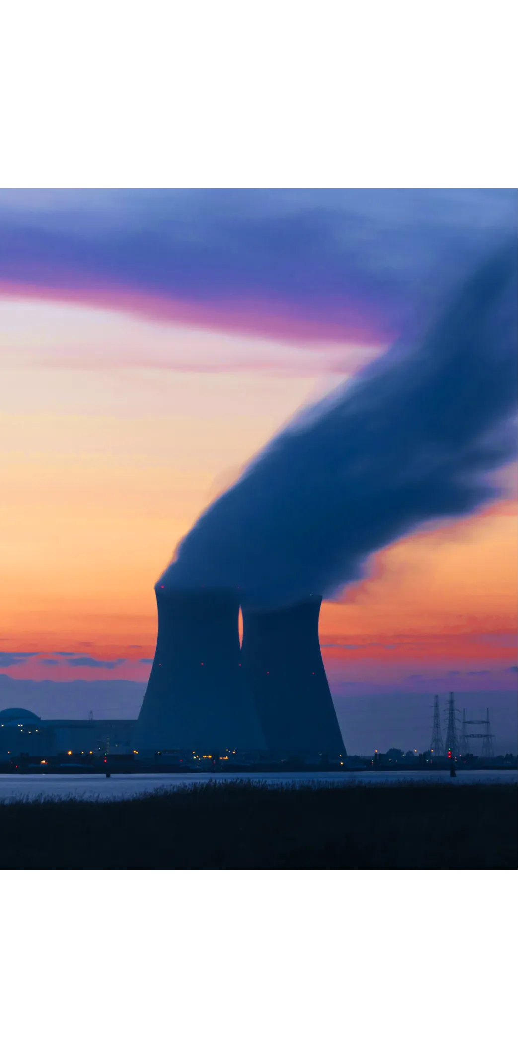 Power plant cooling towers releasing steam at sunset