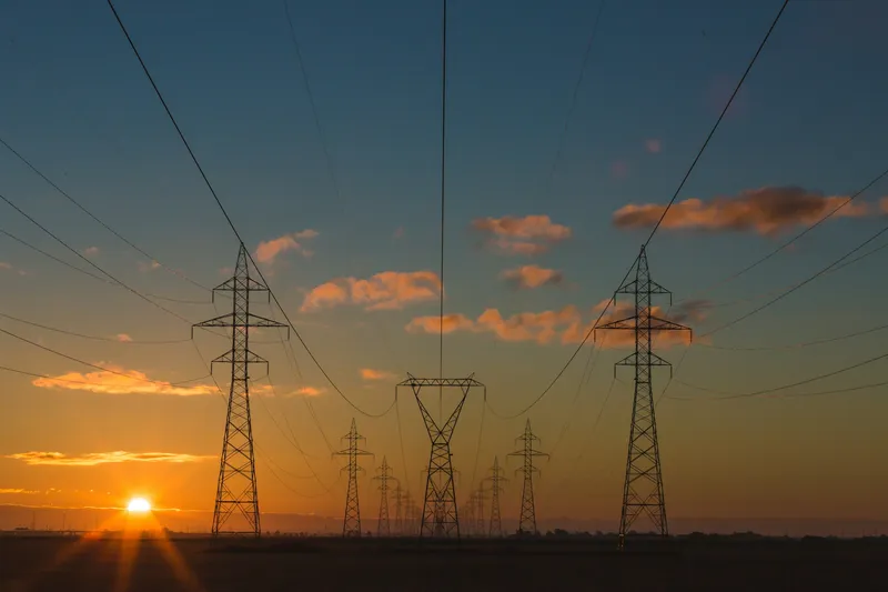 high-voltage transmission towers at sunset