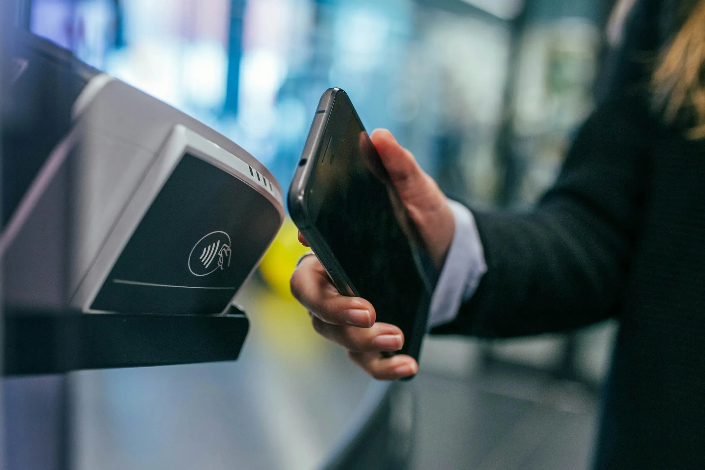 Person holding a smartphone at a contactless terminal (Unsplash, free license)