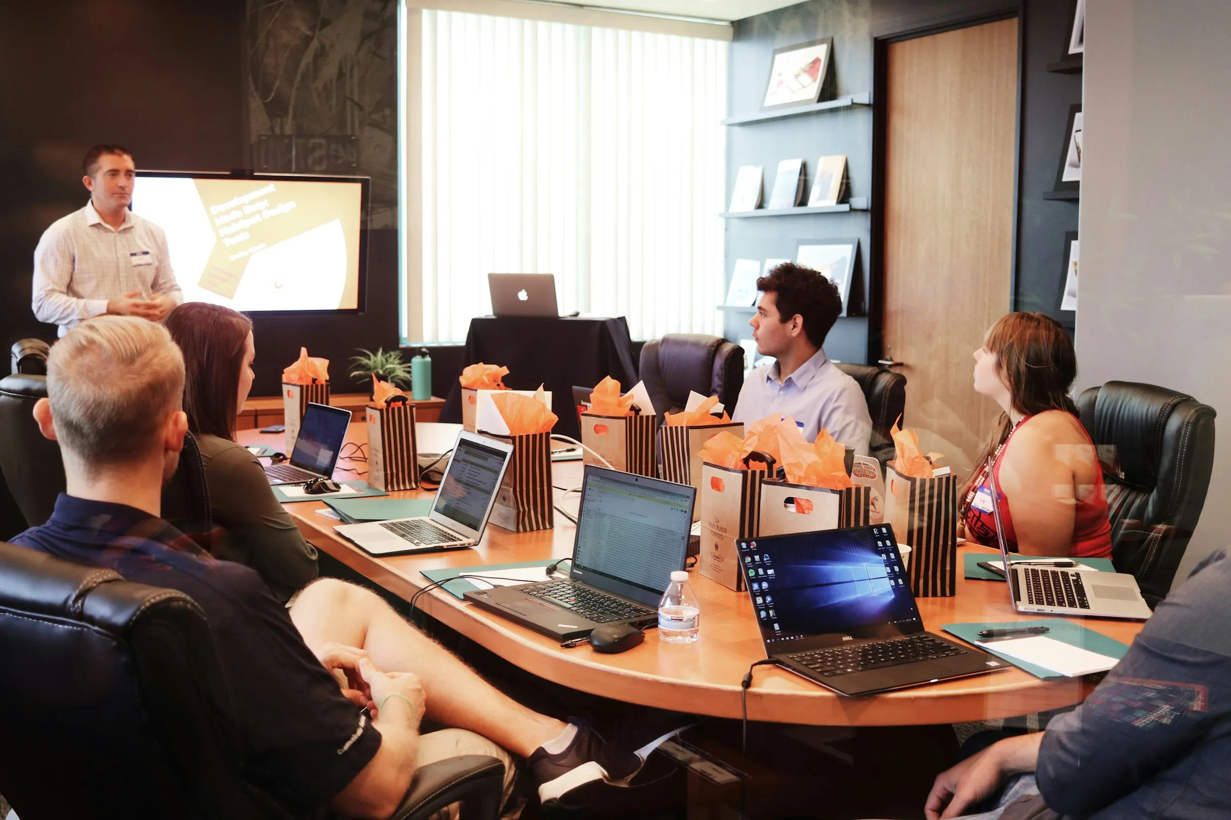 Presentation to a team at a conference table with laptops (Unsplash free license)