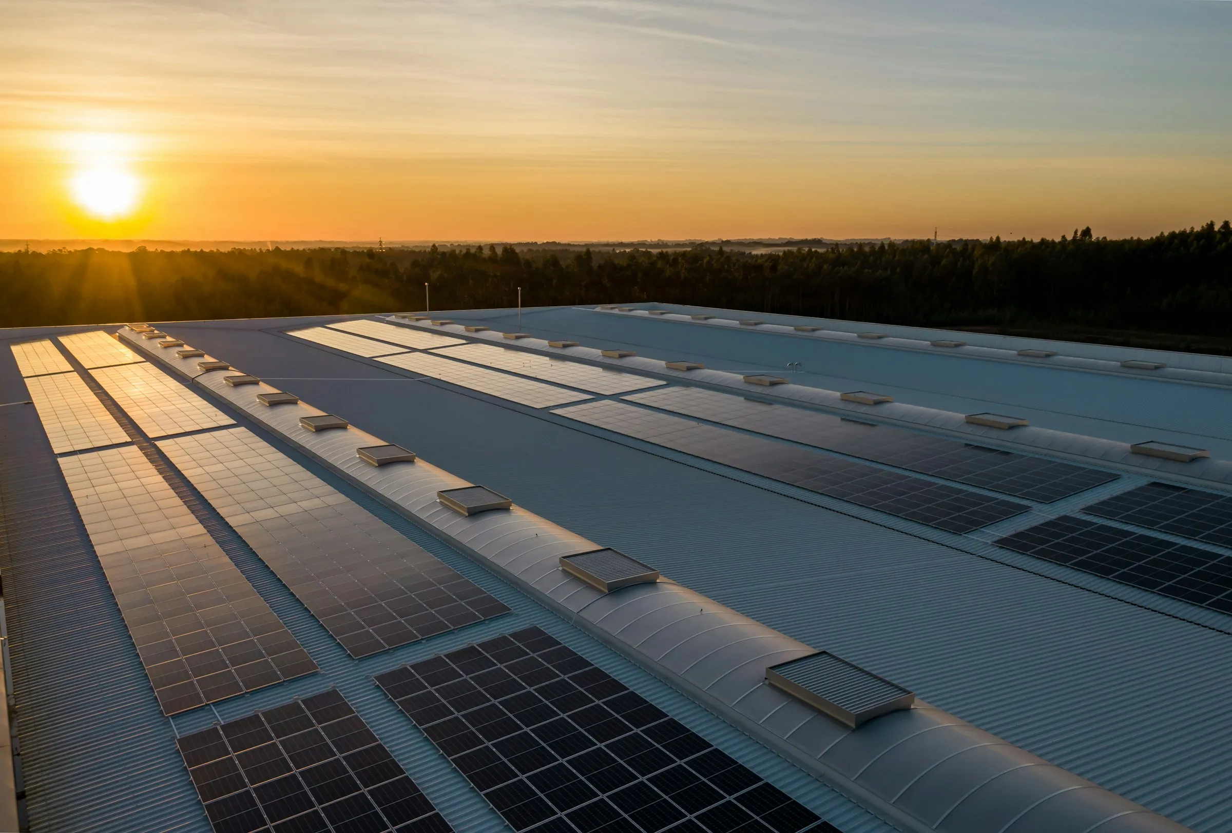 Solar panels on an industrial building roof at sunset (Unsplash free license)